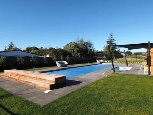 een zwembad met een houten bank naast een tuin bij Pinot Longbox - Martinborough Holiday Home in Martinborough 
