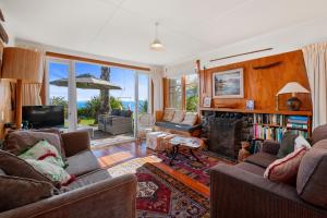 a living room with two couches and a fireplace at North Cole Cottage - Hatepe Lake Front Home in Waitahanui