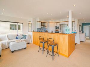 a living room with a couch and a kitchen at Seaview Serenity- Whitianga Holiday Home in Whitianga