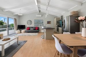 a kitchen and living room with a table and chairs at Pohutukawa Breeze - Papamoa Beach Holiday Home in Papamoa