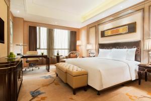 a bedroom with a large white bed and a desk at Wanda Realm Harbin Hotel in Harbin