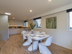 a dining room with a white table and white chairs at Alchemy Cottage - Arrowtown Holiday Home in Arrowtown