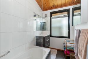 un bagno bianco con vasca e lavandino di Sandy Toes Holiday Home Orewa a Orewa