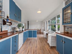 KuratauにあるKuratau Classic - Kuratau Holiday Homeのキッチン(青いキャビネット付)、ダイニングルーム +16枚の写真