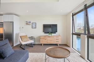 a living room with a couch and a tv at Riverside Villa - Taupo Holiday Home in Taupo