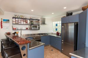 a kitchen with blue cabinets and a stainless steel refrigerator at Captain's Quarters - Opua Holiday Home in Opua