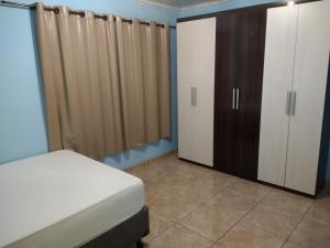 een slaapkamer met een bed, een kast en gordijnen bij Casa Morumbi in Foz do Iguaçu