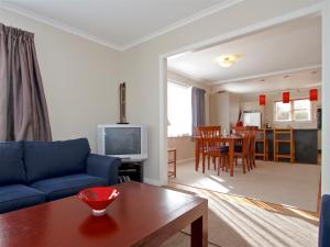 a living room with a blue couch and a table at Raetihi Cottage- Raetihi Holiday Home in Raetihi