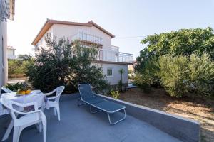 un patio con tavolo, sedie e un edificio di Apartments Ivica - garden terrace a Slatine