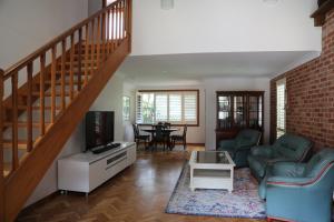 a living room with a staircase and a couch and a table at Pacific Palms Thirroul Beach NSW in Thirroul