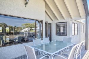 a dining room with a glass table and chairs on a balcony at Central City Gem - Napier Holiday Home in Napier