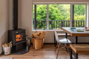 a living room with a stove and a table and a window at La Petite Maison - Akaroa Holiday Home in Akaroa