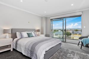 a bedroom with a bed and a large window at Sunrise, Seaviews and BBQs-Papamoa Beach Apartment in Papamoa