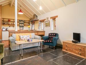 een woonkamer met een bank, een tafel en een tv bij Old Cary Cottage in Langport