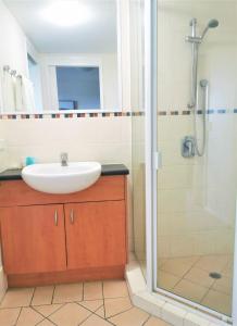 a bathroom with a shower, sink, and tub at The Oasis Apartments in Brisbane