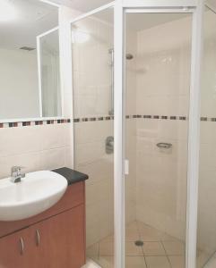 a bathroom with a shower, sink, and mirror at The Oasis Apartments in Brisbane