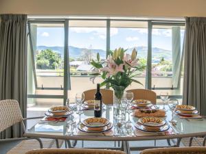 a dining room table with a vase of flowers on it at Rue Noyer Lookout - Akaroa Holiday Home in Akaroa