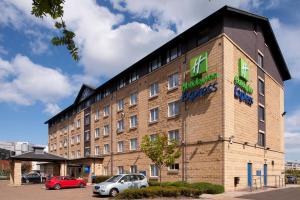 a large brick building with cars parked in a parking lot at Holiday Inn Express Edinburgh - Leith Waterfront by IHG in Edinburgh