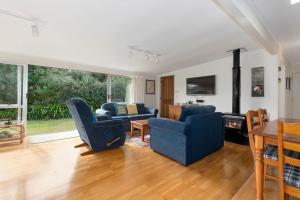 sala de estar con 2 sillas azules y mesa en Matapouri Beach Family Haven - Matapouri Home en Matapouri