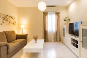 uma sala de estar com um sofá e uma televisão em Alferez I by ELE Apartments em Málaga