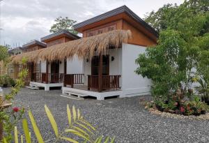 a small house with a straw roof and a porch at Alona Vikings Lodge 1 in Panglao Island