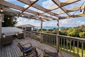una terraza de madera con sofá y sillas. en The Cottage - Snells Beach Holiday Home, en Snells Beach