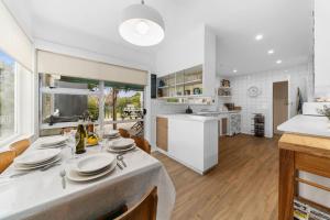 a kitchen and living room with a table with plates on it at Calapso Cottage - Waikanae Beach Holiday Home in Waikanae