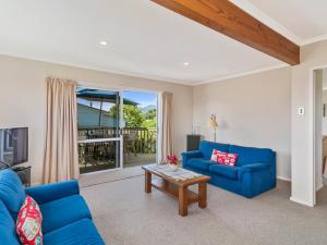 a living room with blue couches and a table at Family at Wharewaka - Wharewaka Holiday Home in Taupo