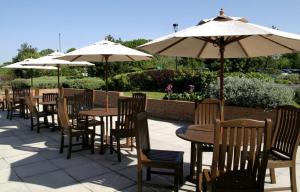 a row of tables and chairs with umbrellas at Holiday Inn Fareham Solent, an IHG Hotel in Fareham