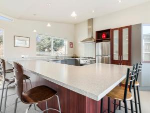 a kitchen with a large white counter top and chairs at Lake Views on Yewlett - Queenstown Holiday Home in Queenstown +13 photos