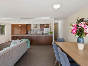 a living room with a couch and a table with flowers at Roberts Retreat - Taupo Holiday Home in Taupo
