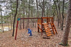 a playground in the woods with a blue fire hydrant at Authentic Log Cabin with Fire Pit, Pond, and More! in Broken Bow