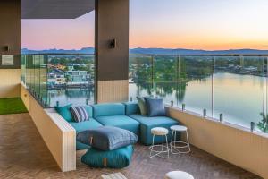 ゴールドコーストにあるPeninsular Gold Coastの青いソファ付きのロビーから水辺の景色を望めます。