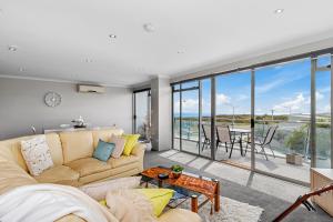 a living room with a couch and a table at Sunrise, Seaviews and BBQs-Papamoa Beach Apartment in Papamoa
