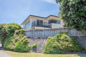 a house on a stone wall with a fence at Sun on Seaview - Paraparaumu Beach Holiday Home in Paraparaumu Beach