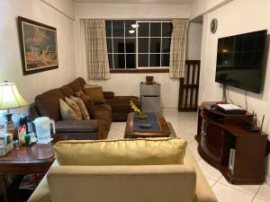 salon z kanapą i telewizorem w obiekcie Apartamentos Comodos Cerca del Aeropuerto w mieście Gwatemala