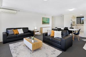 a living room with two black couches and a table at Surfers Century Oceanside Apartments in Gold Coast