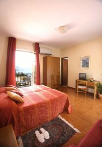 a bedroom with a bed and a desk and a window at Hotel Natalina in Taormina