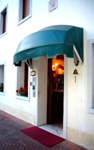 un bâtiment avec un auvent vert surplombant l'entrée d'un restaurant dans l'établissement Albergo La Meridiana, à Portogruaro
