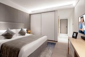 a bedroom with a large bed and a television at Ascott Raffles City Chongqing in Chongqing