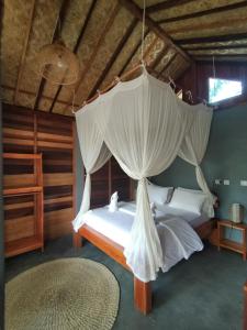 um quarto com 2 camas e uma rede mosquiteira em The Geckos Homestay em Kelimutu