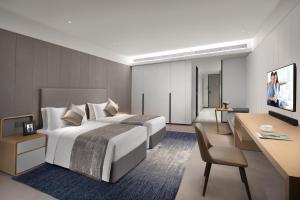 a hotel room with a large bed and a desk at Ascott Raffles City Chongqing in Chongqing
