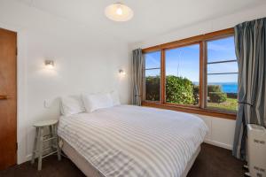 a bedroom with a bed and a large window at North Cole Cottage - Hatepe Lake Front Home in Waitahanui