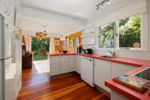 a kitchen with white cabinets and a red counter top at North Cole Cottage - Hatepe Lake Front Home in Waitahanui +15 photos