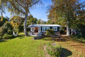 a small house with a hammock in a yard at North Cole Cottage - Hatepe Lake Front Home in Waitahanui