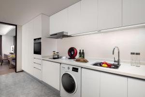 a white kitchen with a sink and a dishwasher at Ascott Raffles City Chongqing in Chongqing
