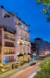 a tall white building on a city street at night at The Q Hotel in Hanoi