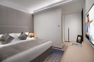 a bedroom with a large bed and a tv at Ascott Raffles City Chongqing in Chongqing