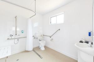 a white bathroom with a toilet and a sink at Torquay Foreshore Caravan Park in Torquay
