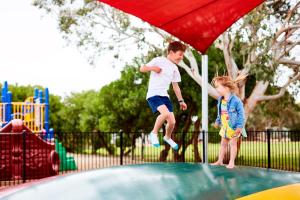 un hombre y un niño saltando en un trampolín en Torquay Foreshore Caravan Park en Torquay